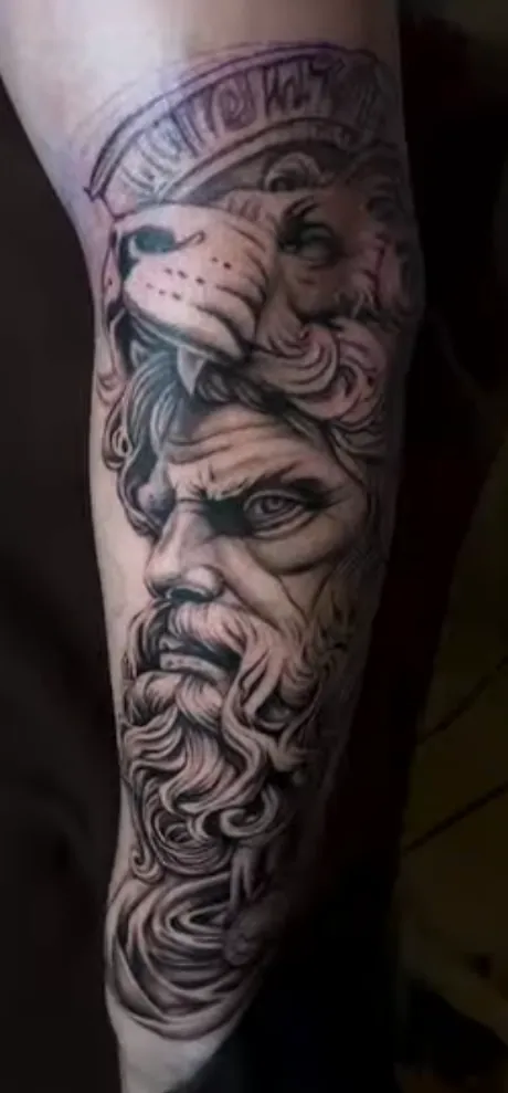 Zeus con piel de león tatuado en el antebrazo, realismo en negro y gris
